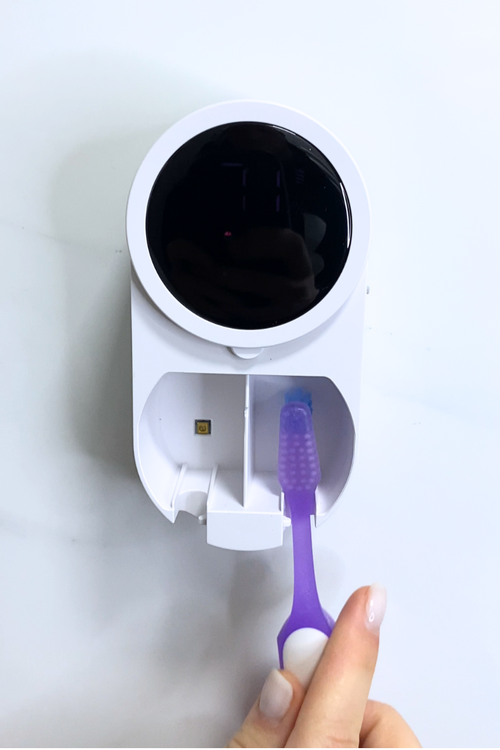 Inserting toothbrushes into PureVee UV toothbrush sanitizer for sterilization.